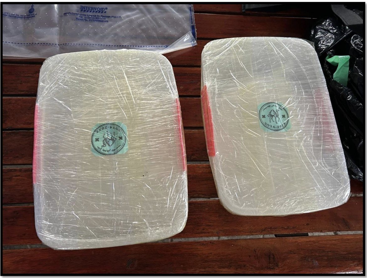 Two shrink-wrapped containers of methamphetamine bearing a green circular marking, photographed on a wooden table.